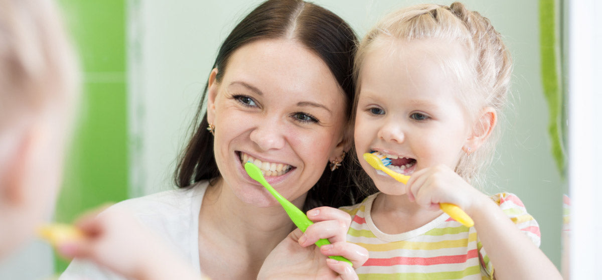 mother and daughter brushing teeth together