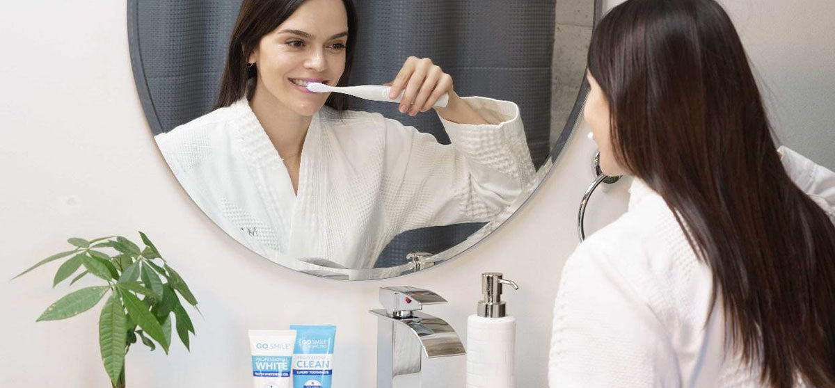woman brushing teeth over sink